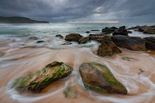 A natural landscape of rocks on the seashore under a cloudy sky