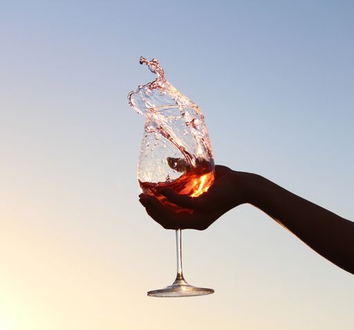A closeup shot of a hand holding a splashing glass of wine