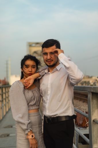 A vertical shot of a couple standing on an old bridge on a windy day in Saigon, Vietnam
