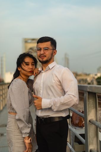A vertical shot of a couple standing on an old bridge on a windy day in Saigon, Vietnam