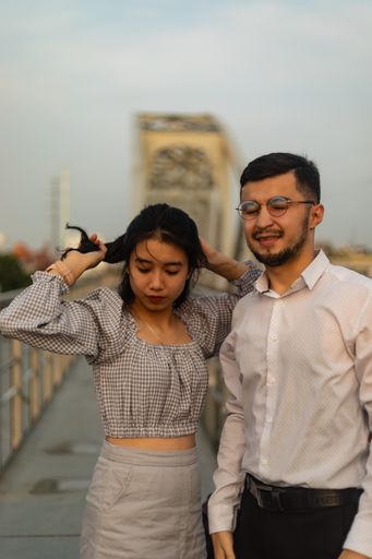 A vertical shot of a couple standing on an old bridge on a windy day in Saigon, Vietnam