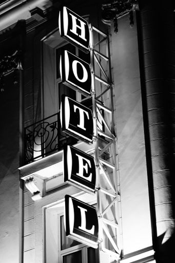 A vertical grayscale shot of a Hotel sign on the bui