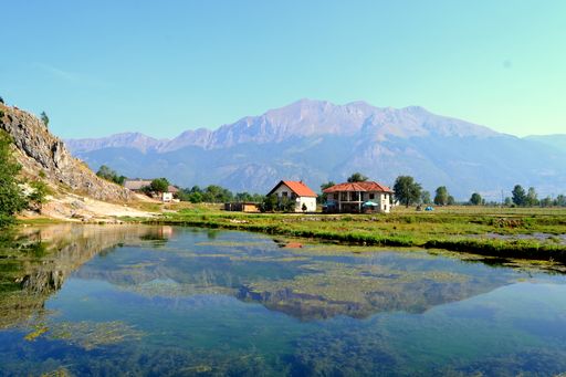 The rural houses near a lake and mountains in the background