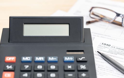 A close up of a Calculator with blank screen and tax form on table.