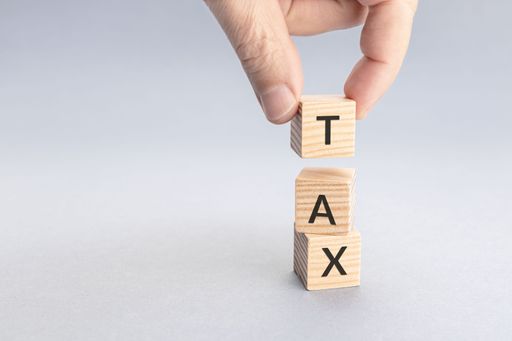 A taxation concept. Hand putting a block with TAX word on top of others. Copy space
