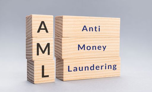 A close up of a AML Anti money laundering text on wooden blocks on gray background