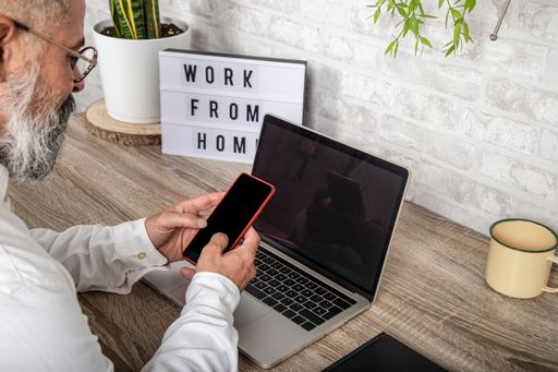 A man using his smartphone while sitting in his home office - the concept of remote work
