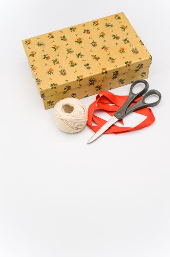 a closed paperboard box with stationery and red ribbon on white background with text space