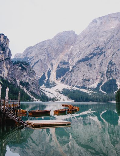 A vertical shot of boats on an icy lake near snowy cliffs in Italy