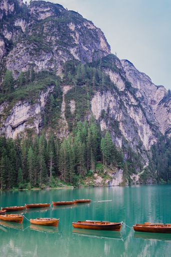 A vertical shot of boats on an icy lake near sharp cliffs in Italy