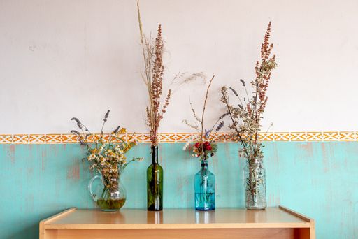 A closeup of four vases full of different flowers on a wooden table