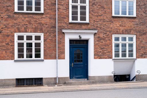Facade of a classic European brick building with a blue door and white-framed windows.