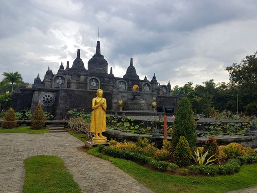 Buddhist monastery in North Bali with stupas, golden Buddha statues, lotus ponds, and lush gardens under a cloudy sky.