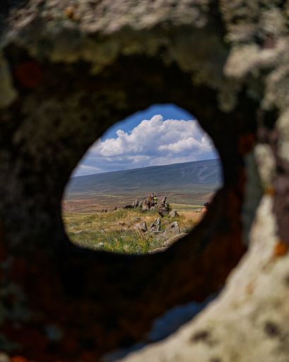 A vertical shot beautiful mountains of Syunik Region of Armenia through a hole in a rock