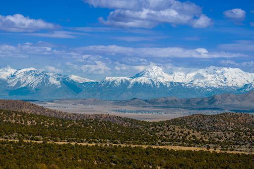 A beautiful view of snowy mountains against a cloudy sky on a sunny day near Utah lake