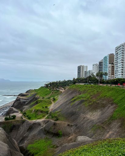 A scenic view of Miraflores cliffs and ocean with modern buildings in Lima, Peru on a cloudy day.