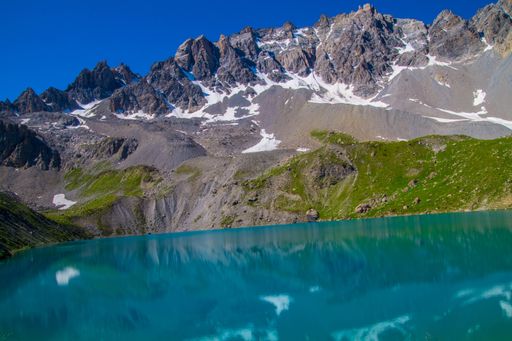 A Mesmerizing view of beautiful snowy hills and a small lake with blue sky in the background
