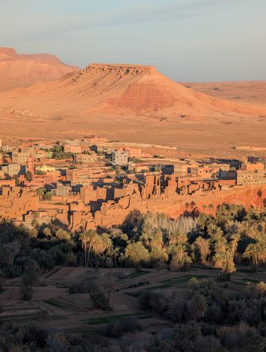 A scenic view of Ait Benhaddou, Morocco, with a desert landscape and traditional adobe buildings