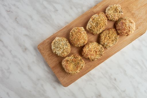 A top view of crispy fried cutlets on a wooden cutting board.