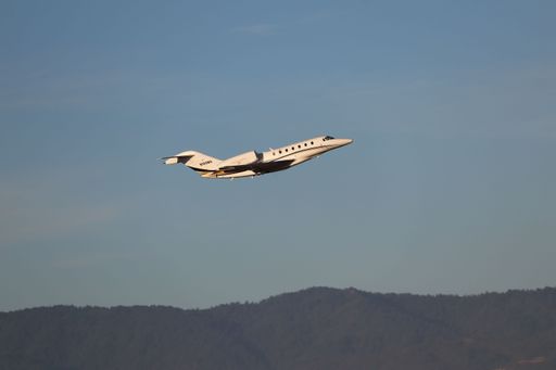 The Cessna Citation X taking off at sunrise from San Jose airport with mountains in the background.