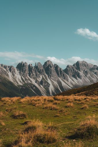 Scenic view of rugged mountains under a clear blue sky with grassy foreground, showcasing natural beauty and tranquility.