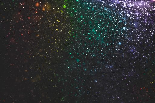 A closeup of colorful glitters on black surface background