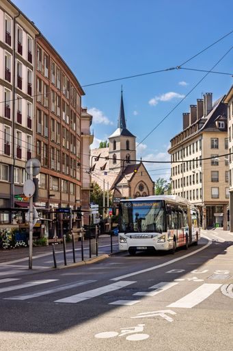 A city street scene in Strasbourg featuring a bus and historic architecture under a clear blue sky.