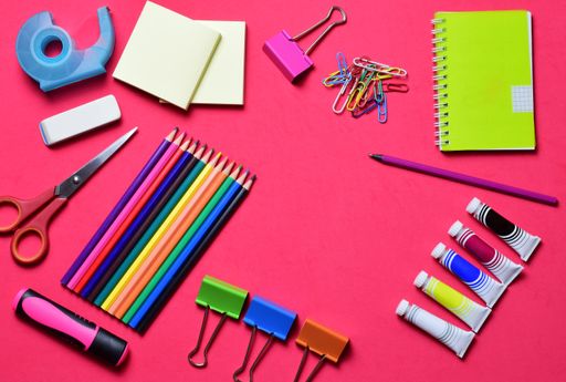 A variety of school supplies, hydroalcoholic gel, and surgical masks on a light-colored background