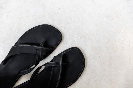 A top view of a pair of black slippers on the white surface