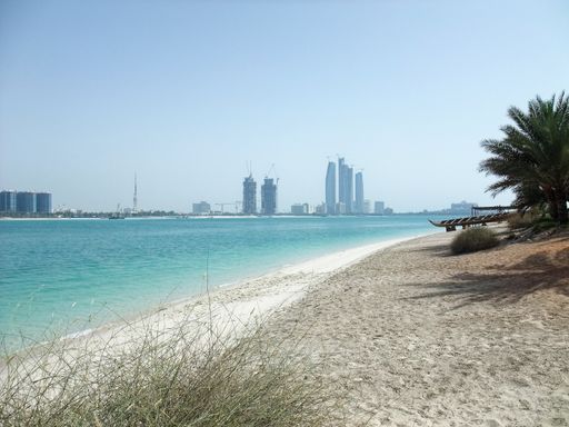 A sandy beach with the skyline of Abu Dhab