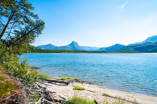 A scenic view of a beachside with a mountain range in the distance on a sunny day