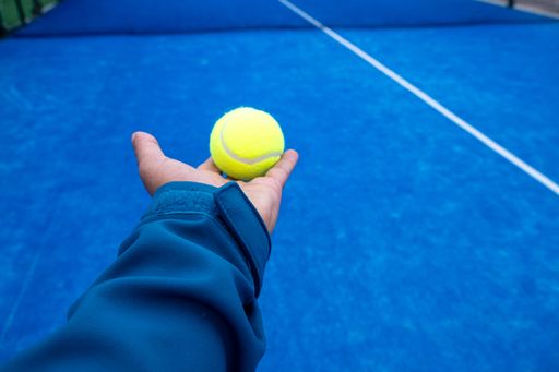 Player holding a yellow tennis ball on a blue court, POV shot.