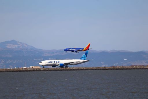 A wide view of an airport terminal with multiple airplanes and the control tower under a clear sky.