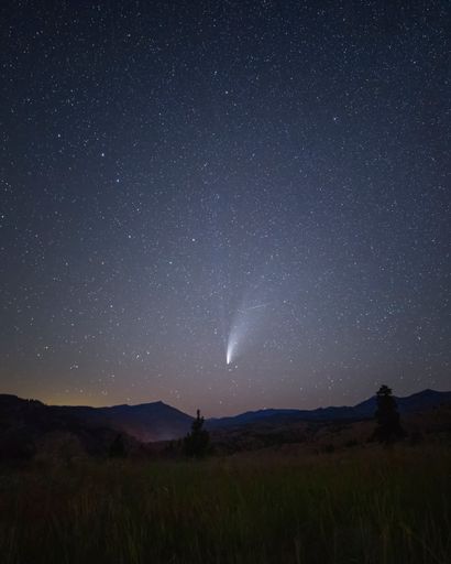 A scenic view of a comet shining on the starry sky over the landscape of Entiat in Washington, USA