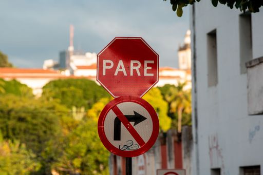 A close-up of a stop sign and no right turn sign with a blurred city background