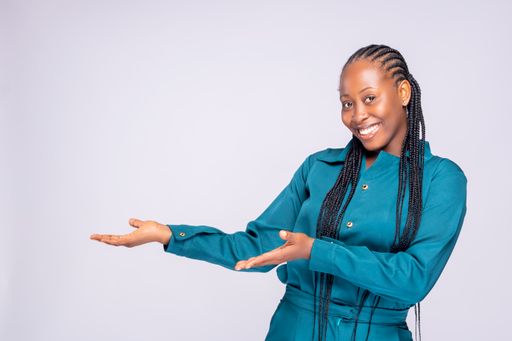 A young African lady from Nigeria posing wearing a blue jumpsuit showing on t left with her hands