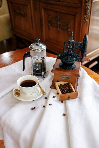 A high angle shot of a coffee machine and coffee beans near a cup of coffee on a white surface