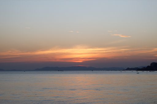 A beautiful shot of the sunset above a sea with some mountains in the background