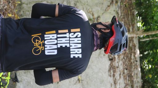 A vertical shot of a man with a t-shirt 'share the road for cyclist'