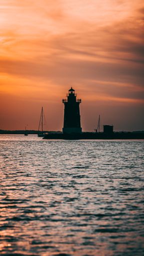 A vertical shot of the Delaware Breakwater East End Lighthouse on a sunset sky background in the USA