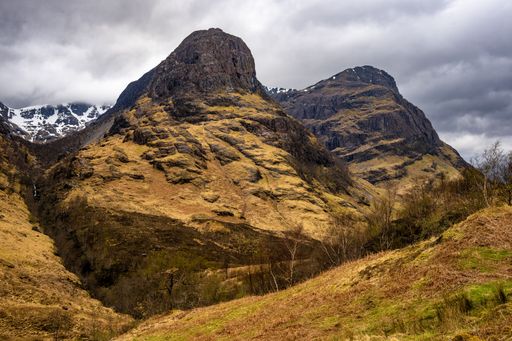 A majestic view of the Three Sisters mountains in Glencoe, Scotland under a dramatic cloudy sky