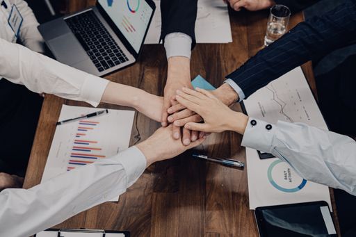 A high angle shot of business partners putting their hands together - unity and teamwork concept