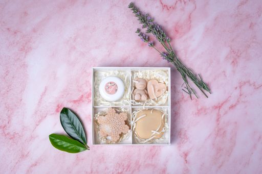 An aesthetic gift box with handmade soaps and lavender on a pink marble background.
