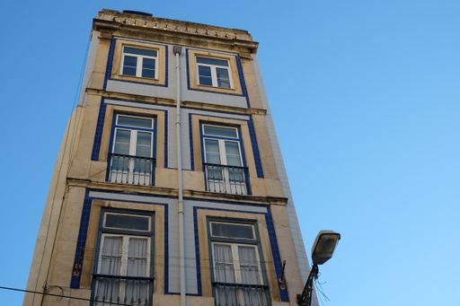A low angle shot of a tall building in Lisbon, Portugal with a clear blue sky in the background