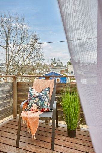 A vertical shot of a chair in the balcony with a pillow and a piece of fabric on it