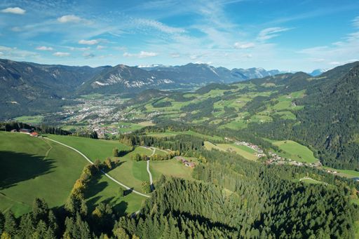 Panoramic aerial view of sunny alpine landscape with green forest, meadows and blue sky. Hiking tourism in Alpbach Valley, Austria.