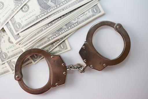 A closeup shot of handcuffs and money on the white table
