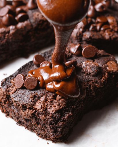 Pouring delicious chocolate ganache on a piece of brownie
