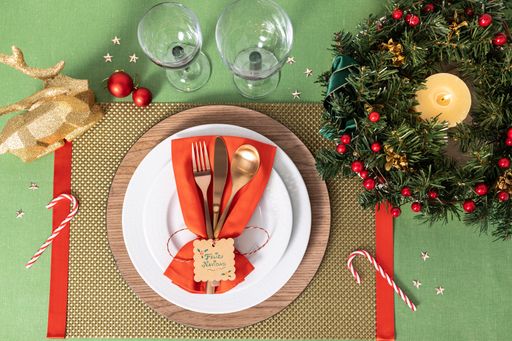 Flat lay of a cozy Christmas table setting, modern cutlery, a festive wreath with a lit candle, creating a holiday atmosphere