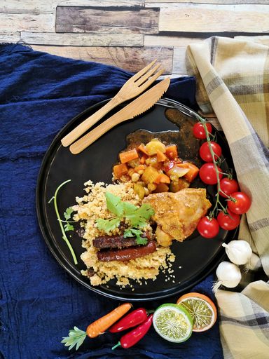 A vertical top view of couscous with tomatoes on the side on the table